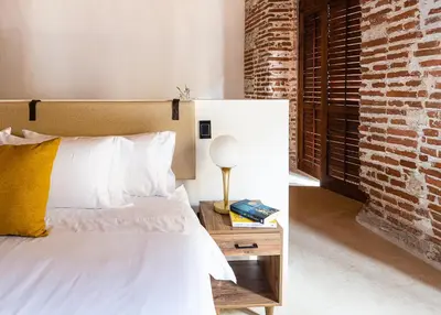 a bedroom with a bed and a brick wall at Hotel Voilá Getsemaní in Cartagena de Indias
