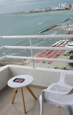 a white bench and a table on a balcony with a beach at Apartamento , vista a la ciudad antigua y playa in Cartagena de Indias