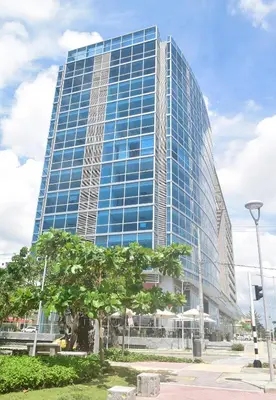 a tall glass building with a tree in front of it at Las Margaritas, Loft en Distrito 90 in Barranquilla