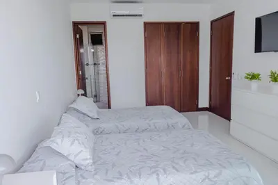 a white bedroom with two beds and a television at apartamento 1 alcoba morros 922 rnt 132107 in Cartagena de Indias
