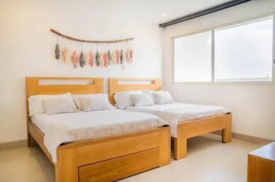 two twin beds in a room with a window at !Condominio de Lujo! Playa + Piscinas + Natural in Cartagena de Indias
