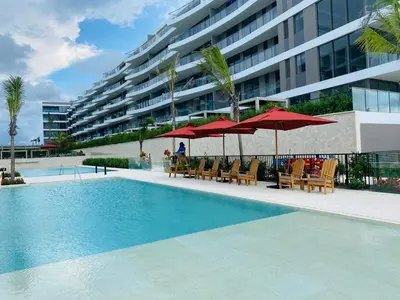 a swimming pool with chairs and umbrellas next to a building at Amazing Loft / Private Beach + Pools + Natural in Cartagena de Indias