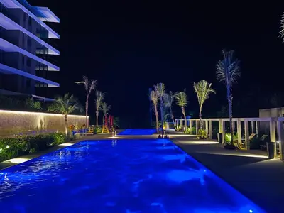a swimming pool at night with palm trees and a building at Amazing Loft / Private Beach + Pools + Natural in Cartagena de Indias