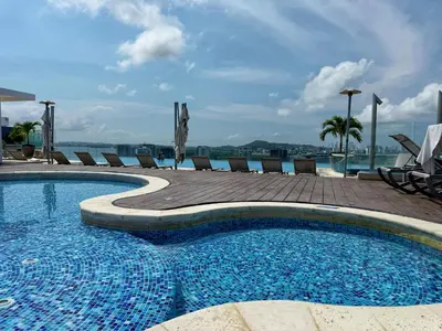 a swimming pool with chairs and a view of the water at ¡Amazing Beach Dúplex! Infinity Pool / Rooftop in Cartagena de Indias