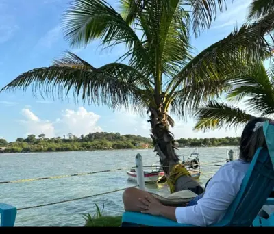 a person sitting in a chair next to a palm tree at Apart Cabaña KTIK in San Bernardo del Viento