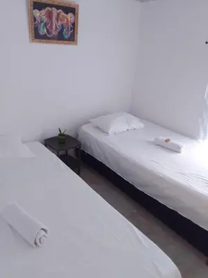 two beds in a bedroom with a picture on the wall at Apart Cabaña KTIK in San Bernardo del Viento