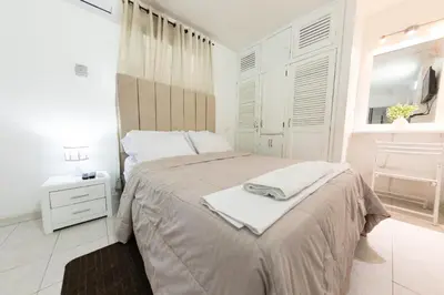 a white bedroom with a large bed and a window at Hostal Casa Dandy in Cartagena de Indias