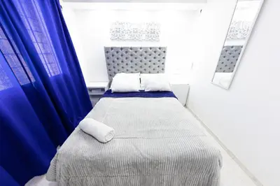 a small bedroom with a bed with blue curtains at Hostal Casa Dandy in Cartagena de Indias