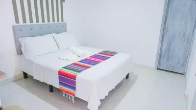 a white bed with a colorful blanket on it at Hotel Playa Divina in Coveñas