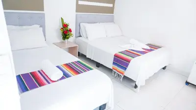 a room with two beds and a table with flowers at Hotel Playa Divina in Coveñas