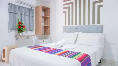 a white bedroom with two beds and a window at Hotel Playa Divina in Coveñas