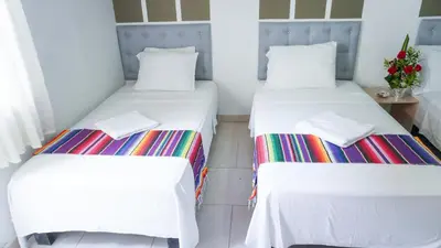 two twin beds in a room with white walls at Hotel Playa Divina in Coveñas