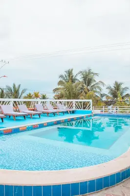 a large swimming pool with chairs and palm trees at Hotel Playa Divina in Coveñas