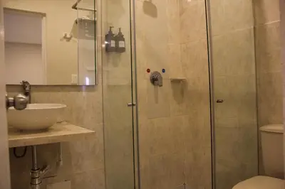 a shower with a glass door next to a sink at Casa Badillo 3 4br LUXURY ROOFTOP oldcity AC jacuzzi hottub wifi in Cartagena de Indias