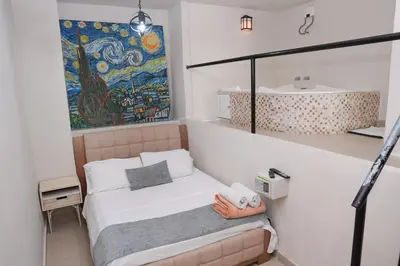 a bedroom with a bed and a painting on the wall at Casa Badillo 3 4br LUXURY ROOFTOP oldcity AC jacuzzi hottub wifi in Cartagena de Indias