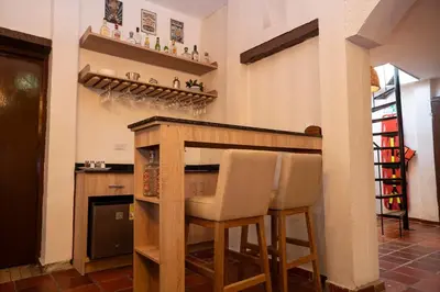 a kitchen with a bar with two stools at Casa Quero 954 COZY HOUSE ROOFTOP POOL AC OLD CITY in Cartagena de Indias