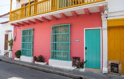 a pink building with green doors on a street at Casa Quero 914, 3br Old city wifi jacuzzi in Cartagena de Indias