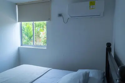 a white bedroom with a bed and a window at Apartasol Amoblado Primer Piso Coveñas in Coveñas