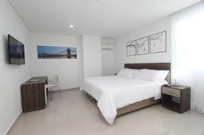 a white bedroom with a bed and a desk at Hotel Oxford Barranquilla in Barranquilla