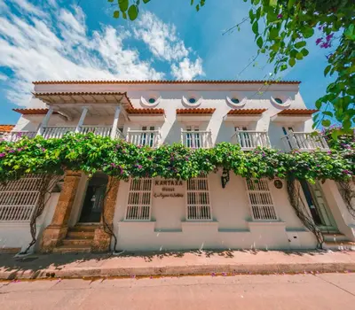 a white house with flowers on the front of it at Hotel Kartaxa in Cartagena de Indias
