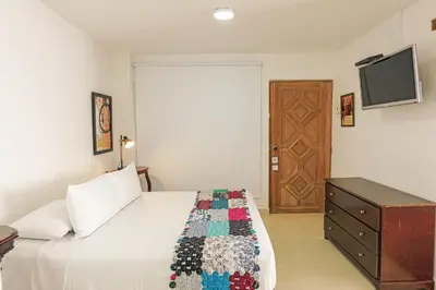 a bedroom with a bed and a dresser and a television at Hotel Kartaxa in Cartagena de Indias