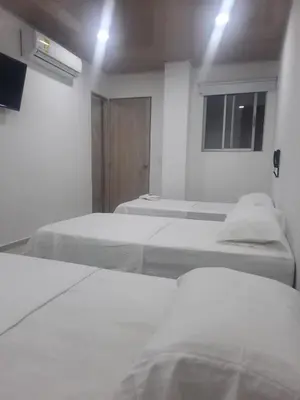a white room with two beds and a window at HOTEL MAR DEL CARIBE in Soledad