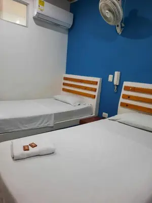 two beds in a small room with a fan at HOTEL MAR DEL CARIBE in Soledad