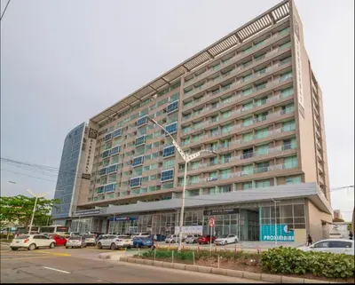 a large building with cars parked in a parking lot at Apartaestudio Amoblado - Distrito90 in Barranquilla