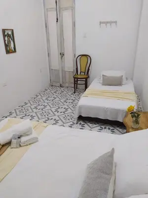 two beds in a white room with a chair at Casa Ego in Cartagena de Indias