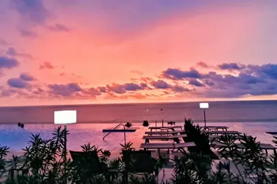 a sunset over the ocean with picnic tables on the beach at Lujoso apartamento Boca grande Condominio H2 in Cartagena de Indias