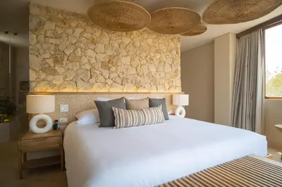 a bedroom with a white bed and a stone wall at Hotel Aimarawa in Coveñas