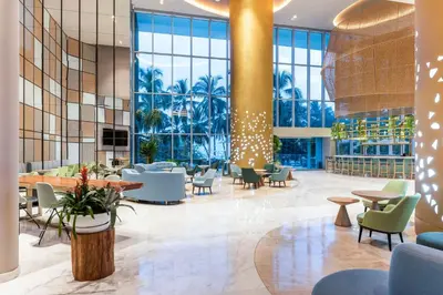 a lobby with tables and chairs and windows at Hilton Santa Marta in Santa Marta