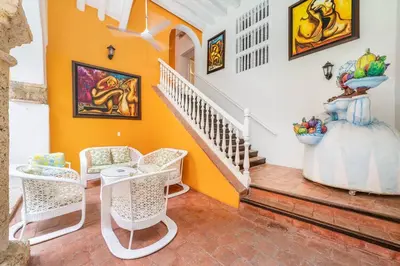 a living room with orange walls and a staircase at Amazing Colonial Mansion Old City Cartagena in Cartagena de Indias