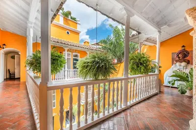 an orange house with a balcony with potted plants at Amazing Colonial Mansion Old City Cartagena in Cartagena de Indias