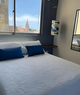 a bed with blue pillows in a room with a window at 417 Apto con vista panorámica de cgna in Cartagena de Indias