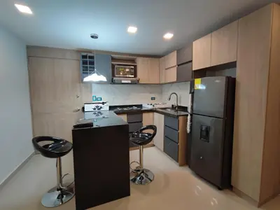 a kitchen with a black refrigerator and two bar stools at APARTAMENTO MODERNO EL LAGUITO JUNTO AL MAR 705 in Cartagena de Indias