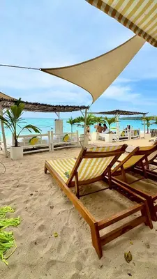 a beach with two chairs and an umbrella on the sand at Mio Mio Beach in Baru