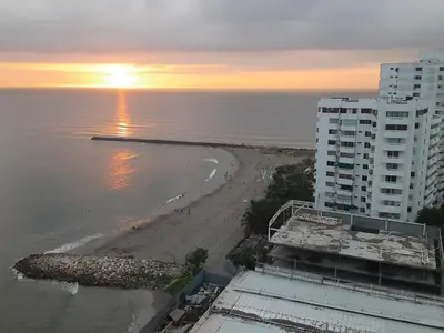 a view of a beach at sunset with a building at Oceanside 3-bedroom apartment in fun tourist area in Cartagena de Indias
