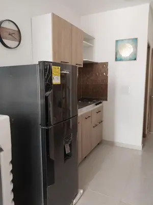 a kitchen with a black refrigerator and wooden cabinets at Cabañas Berakah in Coveñitas