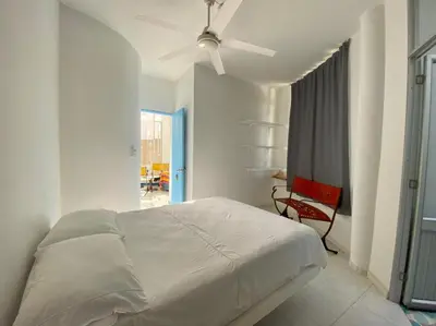 a white bedroom with a bed and a ceiling fan at Casa Amarilla in Santa Veronica