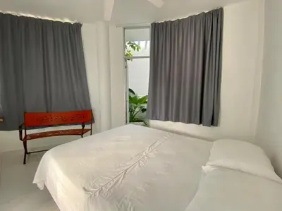 a bedroom with a bed and a chair and a window at Casa Amarilla in Santa Veronica