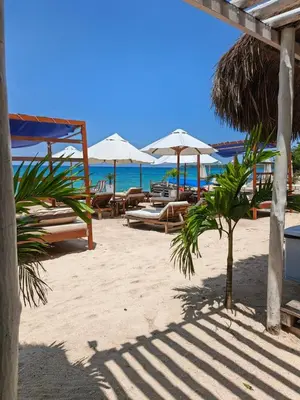 a beach with tables and umbrellas on the beach at Cristal Blue Barú in Baru