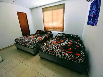 a room with two beds and a window at Casa Pupo Hostal in Cartagena de Indias