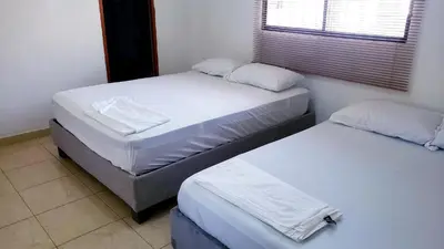 two twin beds in a room with a window at Casa Pupo Hostal in Cartagena de Indias