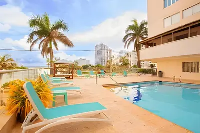 a swimming pool with lounge chairs next to a building at Laurdhomes Laguito Loft Hot Ware 1Bath, lake view in Cartagena de Indias