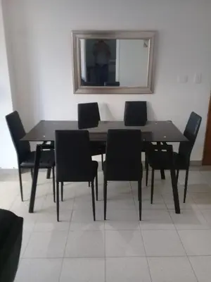 a dining room table with black chairs and a mirror at Condominio en la Playa de Crespo in Cartagena de Indias