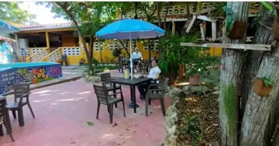 two people sitting at a table with an umbrella at Villa Margarita in Puerto Colombia