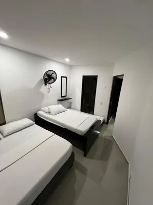 two beds in a room with white walls at Alojamientos Cartagena Edificio Atlantis y Conquistador in Cartagena de Indias