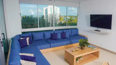 a blue couch in a living room with a large window at Magico Apartamento Frente al Mar 4 Habitaciones PAZ345 in Coveñitas