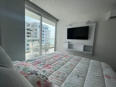a bedroom with a bed and a tv and a balcony at Hermoso apartamento con vista al mar y salida directa a la playa in Cartagena de Indias